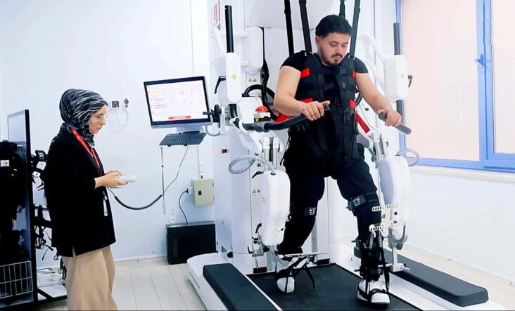 Otomatik taslak cihazıyla yürüyüş ve denge testi yapan kişi, uzmanlar tarafından izleniyor.